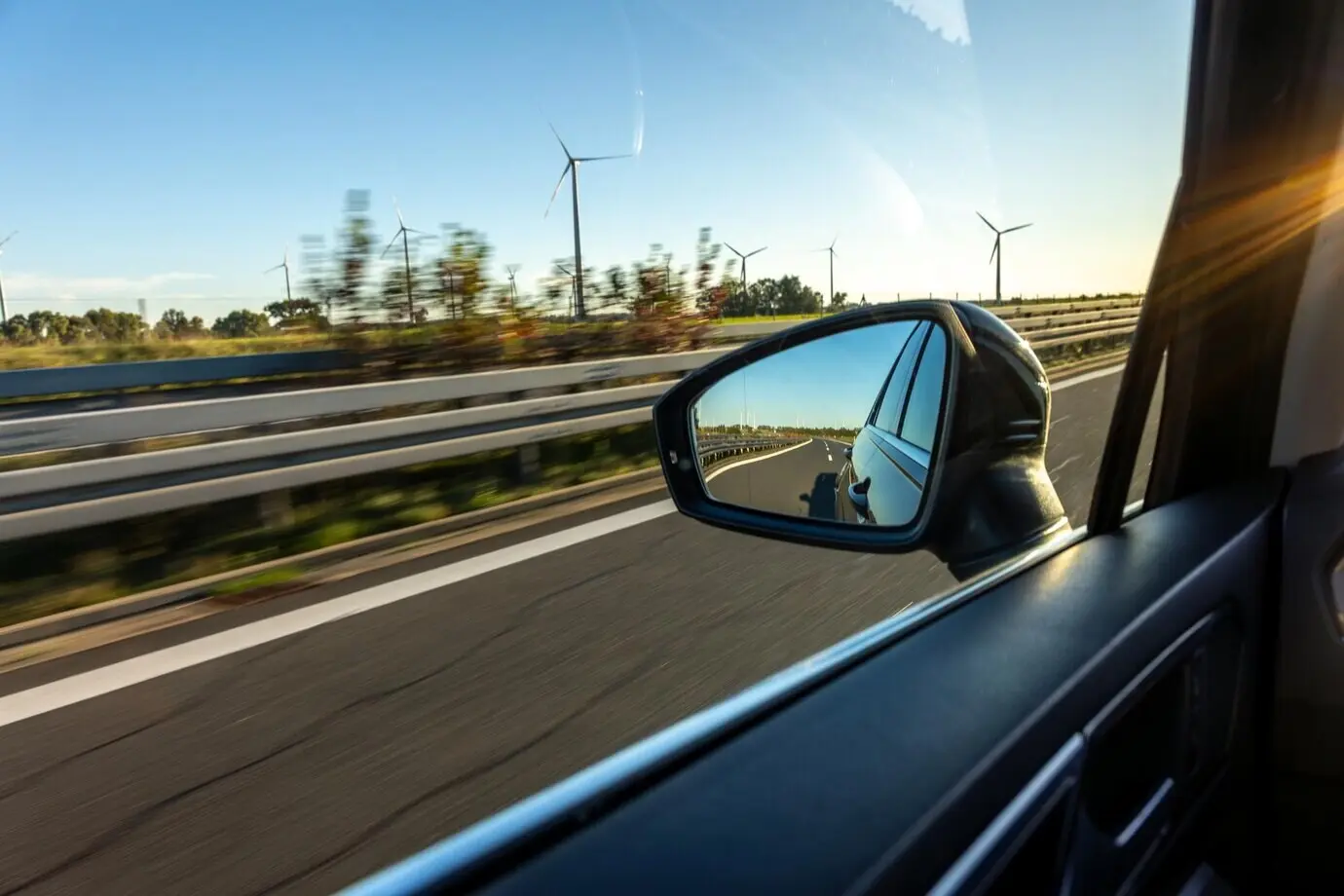 Espejo de automóvil con vista de turbinas eólicas, viaje de estilo ecológico.