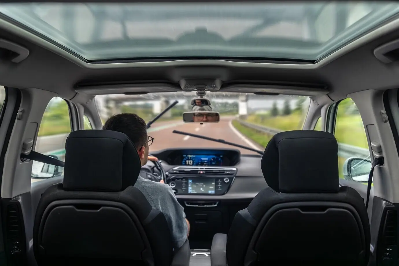 Conductor en carretera mojada tras la lluvia, movimiento tranquilo y enfoque en el viaje.